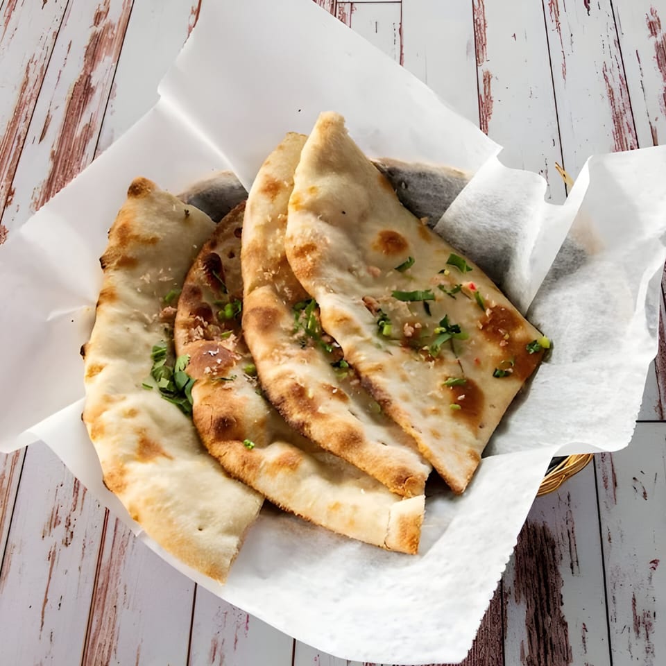 Basket of VEDA Indian Cuisine & Bar naan bread, garnished with herbs and sesame seeds.