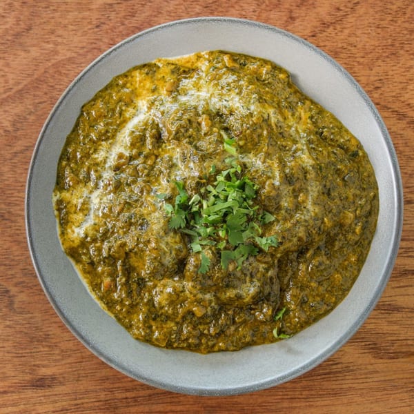 Overhead view of a bowl of vibrant green Indian palak paneer, garnished with fresh cilantro.